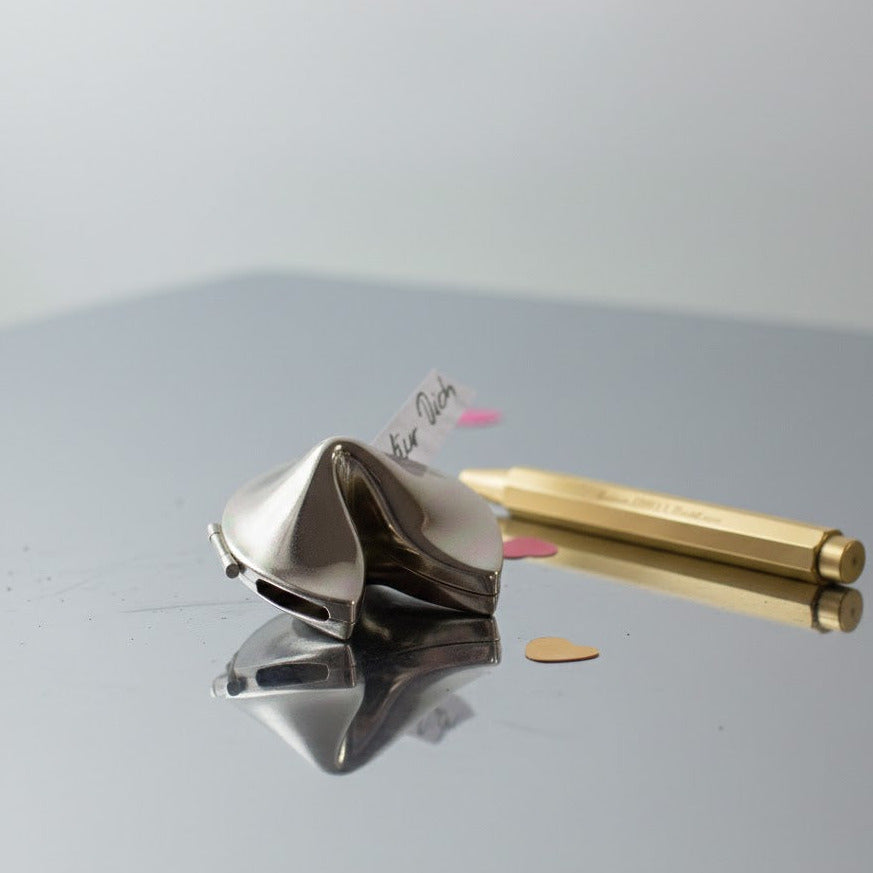 Glückskeks aus Edelstahl auf Chromfläche mit Stift